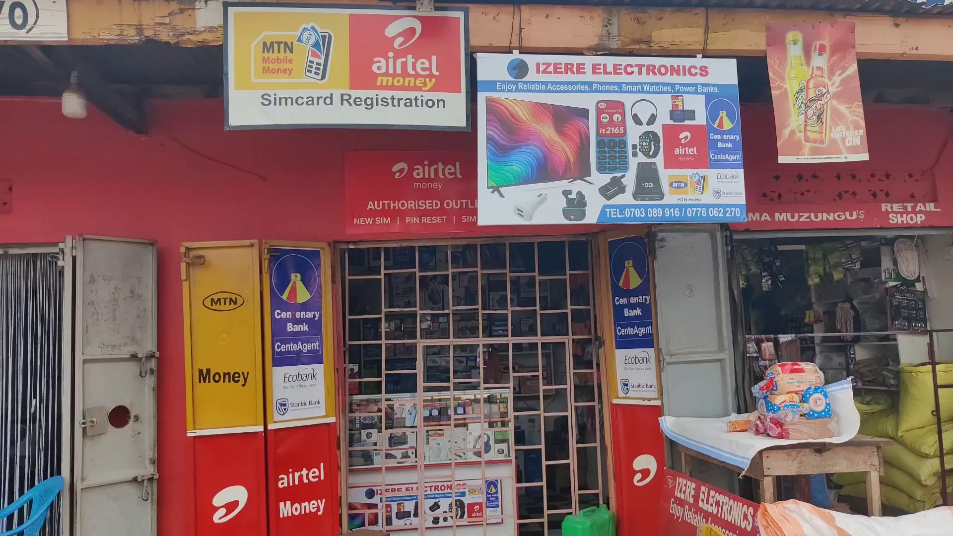 The Izere Electronics shop front in Mikka-Busunju, with its shop sign and mobile money and agent banking branding.